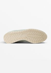 Schuhsohle in hellem Beige mit einer strukturierten, gemusterten Grifffläche; abgerundete Kanten und ein leichter Höhenunterschied an der Ferse; aus Gummi gefertigt.