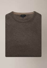 Brązowy sweter z okrągłym dekoltem wykonany z miękkiego dzianinowego materiału, z prążkowanym kołnierzem i metką z rozmiarem, ułożony płasko na neutralnym tle.