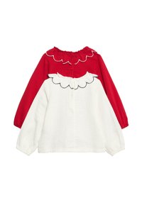 Röd och vit långärmad topp med rund hals, krage med volang och mönstrad design. Gjord av texturerat tyg med knappdetalj.