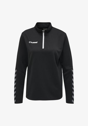 Haut de sport noir à manches longues avec une fermeture éclair blanche au quart, logo « hummel » sur la poitrine et bandes réfléchissantes en chevrons sur les deux manches.