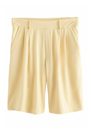 Pantaloncini beige chiaro fino al ginocchio, su misura, con passanti per cintura, pieghe frontali e tasche laterali su sfondo bianco.