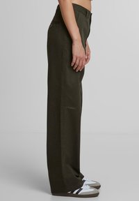 Khaki wijde broek met een zachte textuur en een zijzak, met geborduurde details op het onderbeen, gecombineerd met casual sneakers.