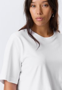 White cotton t-shirt with a crew neckline and short sleeves, featuring a smooth texture and minimalistic design.