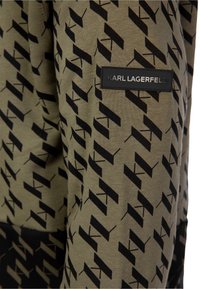 Olijfgroene sweatshirt met een zwart geometrisch patroon, voorzien van een zwart merklabel waarop "KARL LAGERFELD" staat. Zacht, gestructureerd materiaal.