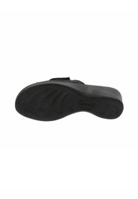 Chaussures noires avec une semelle contournée, un dessous texturé et un talon plat. Équipées d'une sangle en Velcro pour un ajustement et une stabilité réglables.