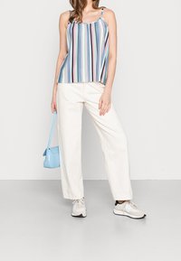 Débardeur rayé en bleu, rose et blanc avec des bretelles réglables ; associé à un pantalon large écru et des baskets légères. Sac à main bleu clair.