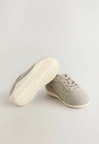 Baskets en suède gris à surface texturée, lacets à l'avant, et semelle en caoutchouc crème avec un motif à chevrons.