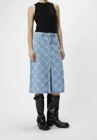 Denimhame, jossa on vaaleansininen väri, timanttikuviot, etuhalkio ja korkea vyötärö, yhdistettynä polveen saakka ulottuviin mustiin nahkakenkiin.