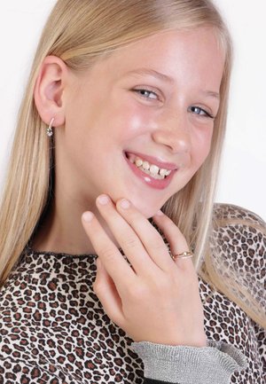 Zilveren hoop oorbellen met kleine stenen, een gouden ring met een golvend ontwerp en edelsteenaccenten, en een top met luipaardprint met een zilveren cuff.