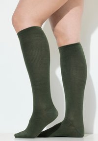 Calze a coste alte fino al ginocchio di colore verde scuro. Realizzate in un materiale morbido ed elastico con rinforzi sulle punte e sui talloni.