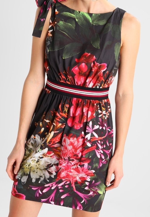 Robe noire sans manches avec un grand imprimé floral coloré et une ceinture rayée, avec un nœud noué sur une épaule.