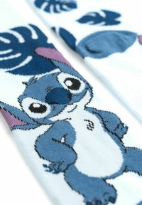 Calzini blu e bianchi con un design lavorato a maglia di un personaggio dei cartoni animati con grandi occhi e una bocca larga, accentuati da dettagli viola.