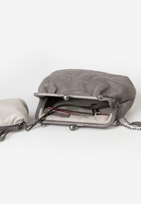 Borsa in pelle grigia con forma arrotondata, dotata di una tracolla a catena e una borsa in tessuto a righe. L'interno presenta una fodera stampata e diversi scomparti.