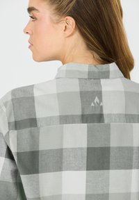 Grå og hvidternet skjorte med krave, knaplukning og et logo på den øverste ryg. Blødt materiale med en struktureret finish.