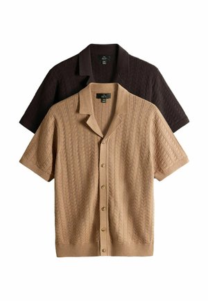 Kaks lühikeste varrukatega kootud kardigani, üks beež ja teine tumepruun, ees nööpidega ja tekstuursete v-mustritega, laotatud valgele taustale.