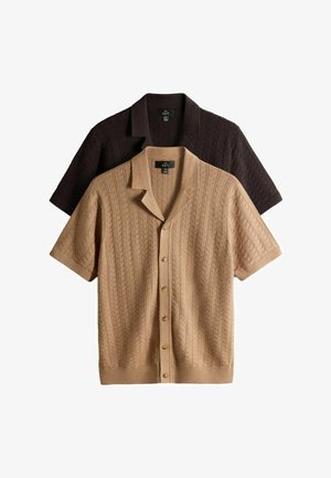 Kaks lühikeste varrukatega kootud kardigani, üks beež ja teine tumepruun, ees nööpidega ja tekstuursete v-mustritega, laotatud valgele taustale.