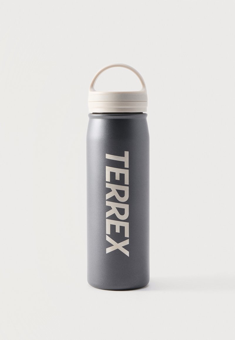 Σκούρο γκρι παγούρι νερού με λευκό καπάκι λαβής, όρθιο, με την επιγραφή "TERREX" κάθετα σε μεγάλα λευκά γράμματα.