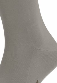 Calza grigia lavorata a maglia con una texture liscia, caratterizzata da un design senza cuciture e sottili coste lungo il corpo, priva di marchi visibili o motivi.