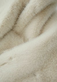 Crèmekleurige nepbontstof met een zachte, pluche textuur, voorzien van een lichte glans en subtiele kleurvariaties.