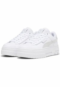Zapatillas blancas con parte superior de cuero suave, que presentan una suela de plataforma ligeramente elevada, cordones planos y un detalle de ante en el lado.