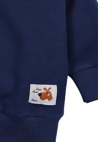 Granatowy materiał bluzy z ribbami, z białą prostokątną metką z rysunkiem psa i tekstem "How How How".