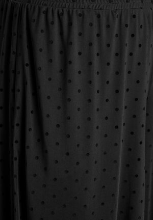 Sort gennemsigtigt stof med hævede fløjlsprikker og elastisk, rynket taljebånd på et nederdel eller kjole.