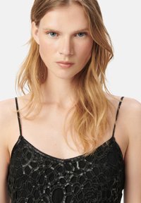 Camisola nera con un intricato motivo di paillettes sulla parte anteriore, spalline sottili e regolabili, e una morbida texture del tessuto.