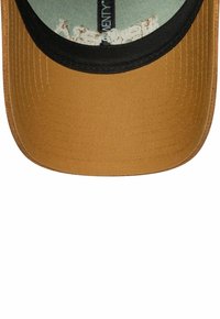 Brauner Hut mit flachem Schirm, aus strukturiertem Stoff. Die Innenseite ist mit einem hellblauen Futter mit einem dezenten Muster versehen. Schwarze Einfassung entlang des Schirms.