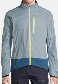 Veste légère et résistante à l'eau de couleur gris clair, avec une fermeture éclair à l'avant de couleur jaune vif et un ourlet et des accents de couleur bleu marine.