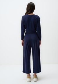 Marineblaues Loungewear-Set mit lässiger Passform, langen Ärmeln, einem elastischen Bund und weiten Hosenbeinen. Glatte Textur, lässiges Design.