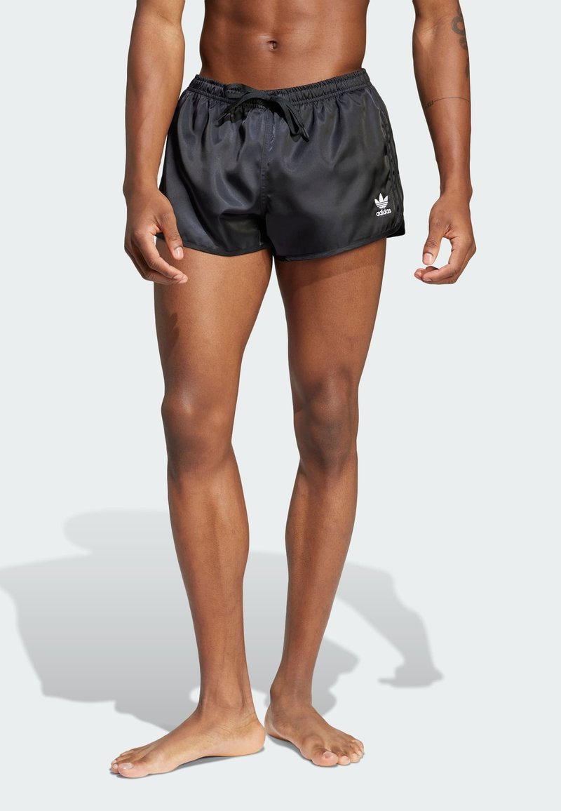 Schwarze Badehosen aus einem glänzenden Material, mit einem elastischen Taillenbund mit Kordelzug und einem kleinen weißen Logo an der Seite.