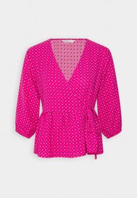 Blouse cache-cœur rose vif à manches trois-quarts avec un petit motif diagonal blanc, noir et rose, nouée à la taille.