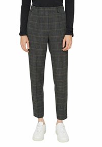 Grijze geruite broek met een getailleerde pasvorm, gemaakt van geweven stof. Voorzien van een taille op mid-rise en taps toelopende enkels. Gecombineerd met witte sneakers.