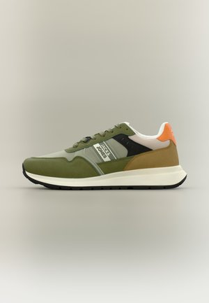 Pantof sport cu talpă joasă, în nuanțe de verde, maro, negru și portocaliu, cu talpă albă, branduit "Jack & Jones" pe panoul lateral, pe fundal neutru.