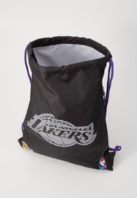Sac à cordon noir en nylon avec une texture lisse, présentant le logo "Los Angeles Lakers" avec des accents blancs et violets, ainsi qu'un logo NBA sur le côté.