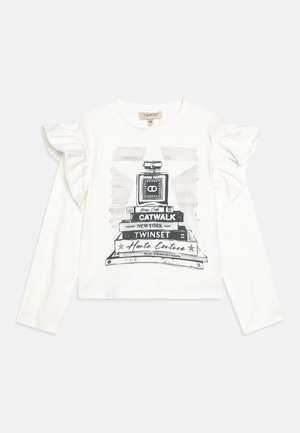 Hvid langærmet skjorte med flæseærmer, prydet med en sort grafik af en parfume flaske på stablede bøger, trykt tekst og stjerneaccents.