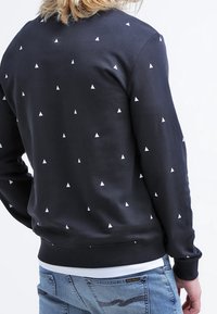 Felpa nera con collo rotondo, con un motivo ripetuto di piccoli triangoli bianchi, polsini e orlo a coste in un fit casual.