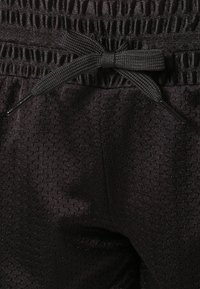 Svarta träningsshorts i ett strukturerat, ventilerande tyg. Har en knytbar dragsko i midjan och fina perforeringar för ventilation.