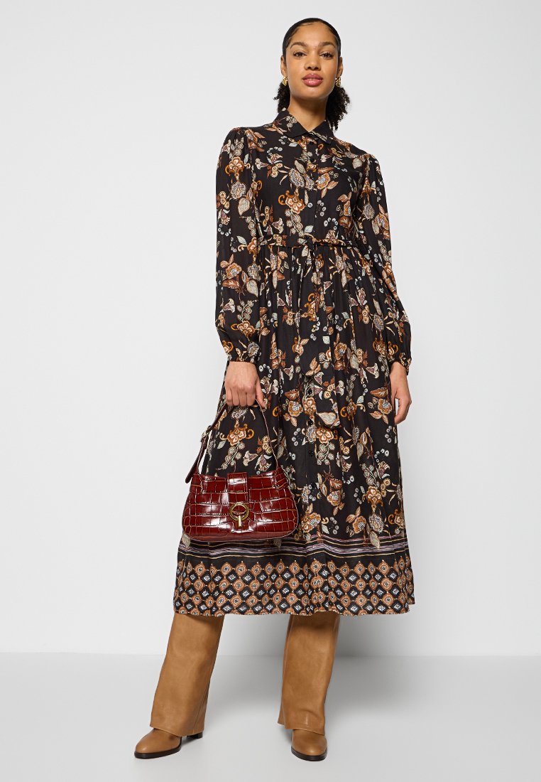 Lungo abito nero con stampa floreale in arancione e bianco, dotato di colletto e vita cinched; abbinato a una borsa in pelle di coccodrillo color bordeaux.