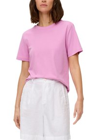 Roze katoenen T-shirt met korte mouwen en een ronde halslijn, gecombineerd met witte linnen shorts met een knoop en geplooide design.