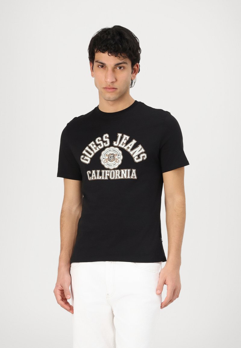 Camiseta de algodón negra de manga corta con el logo "Guess Jeans California" en blanco y marrón. Corte ajustado con escote redondo.