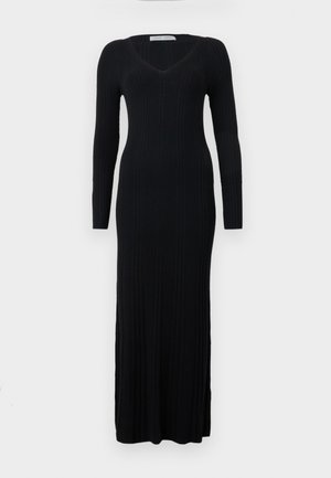 Rochie neagră, din material cu nervuri, cu mâneci lungi, decolteu în V și o siluetă ajustată, care se extinde până la gleznă. Materialul prezintă o textură verticală.