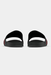 Μαύρα σανδάλια-σλάιντ με ανοιχτή πίσω πλευρά, με κόκκινες και λευκές ρίγες στα πλάγια και λείο υφή πέλματος.