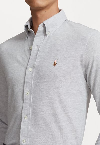 Light gray button-up shirt made of textured fabric, featuring a classic collar and a small embroidered logo on the left chest.