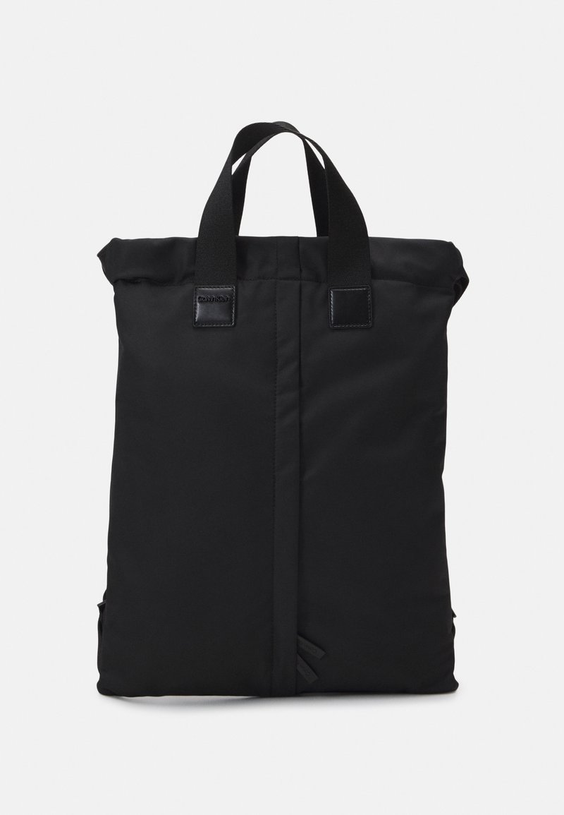 Zaino roll-top nero con manici piatti, realizzato in tessuto resistente. Dotato di tasche laterali e dettagli neri lucidi. Design semplice e geometrico.