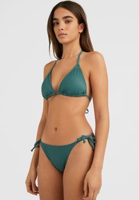 Teal bikini set met een triangeltop met verstelbare strikken en bijpassende low-rise slipjes met zijstrikaccenten. Glad textuur van de stof.
