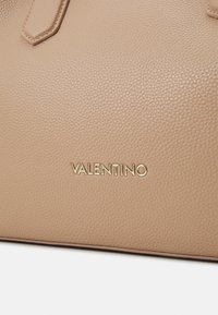 Bolsa de mão em couro bege com textura em pedra, forma elegante e logótipo "Valentino" em tom dourado na frente.