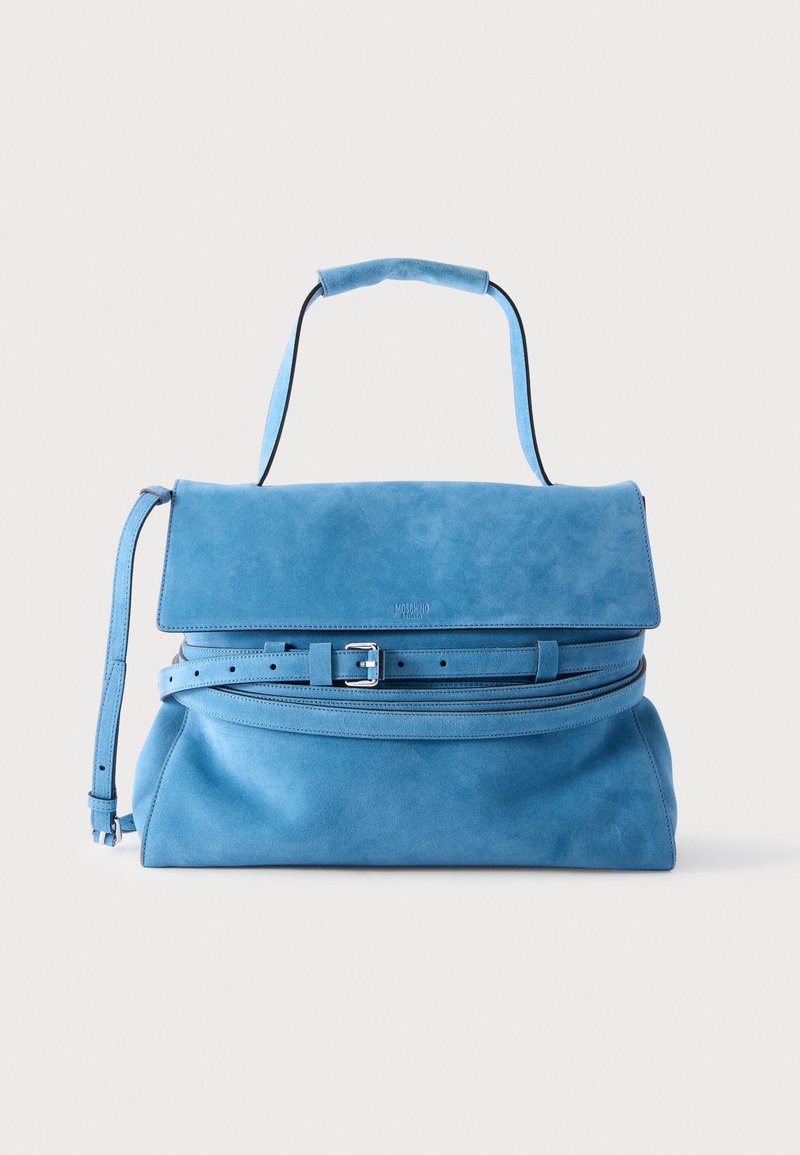 Sac à main en daim bleu avec poignée supérieure, rabat avant et détail de ceinture réglable, présenté sur un fond clair uni.