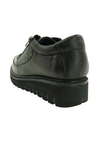 Zapato de cuero negro con suela gruesa y con dibujo, cremallera lateral y detalles acolchados en la parte superior, mostrado desde un ángulo lateral trasero.