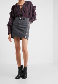 Tmavě květinová blůzka s volánovými rukávy, spárovaná se šedou denimovou mini sukní s bočním zipem. Černé špičaté kotníkové boty dotvářejí celý outfit.